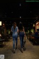 Two women walking down a sidewalk at night. 