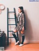 A woman in a school uniform leaning against a ladder.