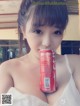 A woman in a white dress holding a can of soda.