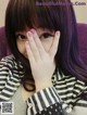 A woman with purple hair covering her face with her hands.