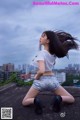 A woman in a white shirt and silver shorts posing on a rooftop.