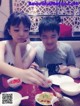 A boy and a girl sitting at a table eating food.