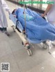 A person laying on a gurney in a hospital hallway.