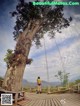 A woman standing on a wooden platform next to a tree.