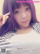 A young woman with purple hair and a striped shirt.