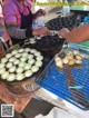 A woman in an apron preparing food on a grill.