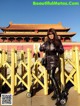 A woman standing in front of a yellow fence.