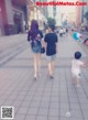 A man and a woman walking down a sidewalk with a child.