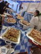 A group of people standing around a table filled with food.