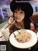 A woman sitting at a table with a plate of food and a drink.