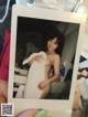 A person holding up a polaroid photo of a naked woman.