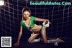 A woman in a bikini holding a soccer ball in front of a goal.