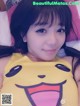 A woman laying in bed wearing a yellow shirt with a smiley face.