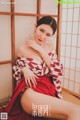 A woman in a red and white kimono sitting on the floor.