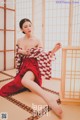 A woman in a red and white kimono sitting on the floor.