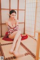 A woman in a red and white dress sitting on a tatami mat.