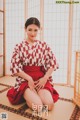 A woman in a red and white kimono sitting on the floor.