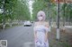 A woman in a white dress and a face mask standing in the middle of a road.