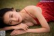 A woman in a red dress laying on the grass.