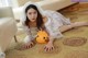 A woman in a white dress laying on the floor next to a pumpkin.