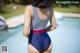 A woman in a blue and red swimsuit standing by a pool.