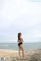 A woman in a black bathing suit standing on a beach.