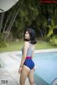 A woman in a blue and red bathing suit standing next to a pool.