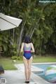 A woman in a bathing suit standing next to a pool.