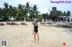 A woman in a black bathing suit standing on a beach.