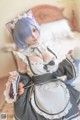 A woman dressed in a maid outfit sitting on a bed.