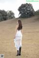 A woman in a white dress standing in a field.