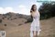 A woman in a white dress standing in a field.