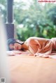 A woman laying on a bed in a pink dress.