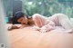 A woman laying on top of a bed in a pink robe.