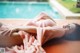 A woman laying on the ground next to a swimming pool.