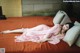 A woman laying on a bed in a pink dress.