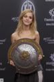 A woman holding a large metal shield in her hands.