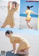 A woman in a yellow dress is posing on the beach.