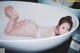 A woman laying in a bathtub with her feet up in the water.