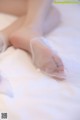 A woman laying on top of a bed covered in white sheets.