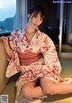 A woman in a red and white kimono sitting on the floor.