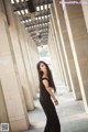 A woman in a long black dress standing in an archway.