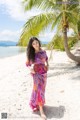 A woman standing on a beach next to a palm tree.