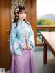 A woman in a blue and purple hanbok standing in front of a window.