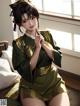 A woman in a green kimono sitting on a bed.