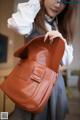 A woman in a school uniform holding a brown bag.