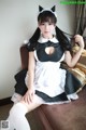 A woman in a maid outfit sitting on a couch.