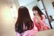 A woman in a pink robe brushing her teeth in front of a mirror.