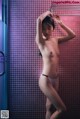 A naked woman standing in a bathroom next to a shower.