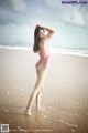 A woman in a pink bikini standing on a beach.